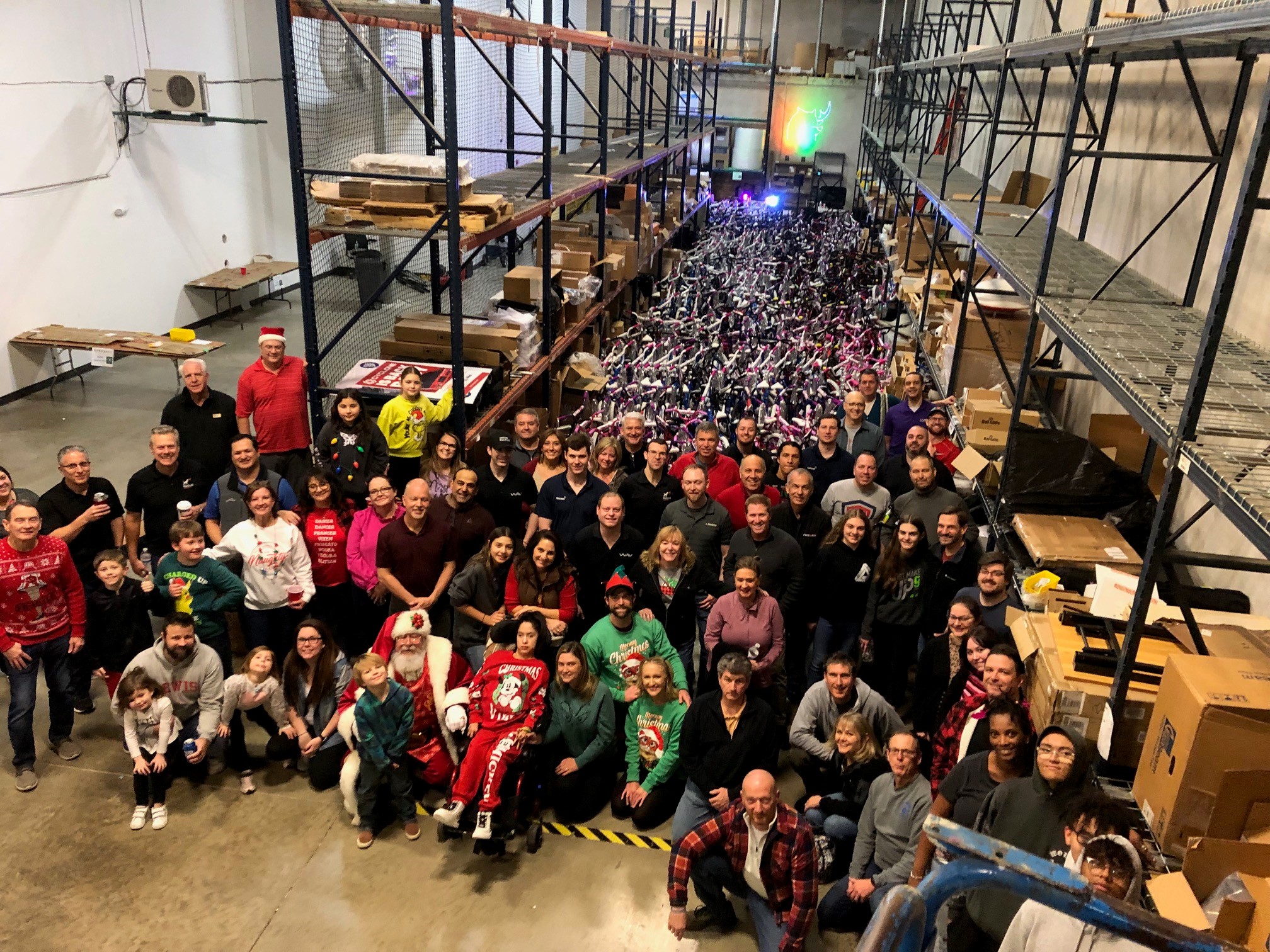 A group of people standing in front of a warehouse full of bikes